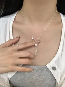 Detail of silver starfish necklace with pearls and blue beads on a woman neck