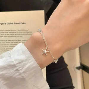 S925 sterling silver starfish bracelet with blue gemstone on a woman's wrist
