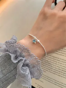 Détail d'un bracelet en argent avec breloque étoile bleue porté par un mannequin