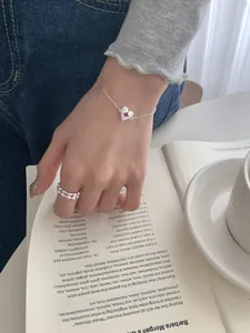 Detail of silver heart bracelet with pink gemstone and textured ring on model
