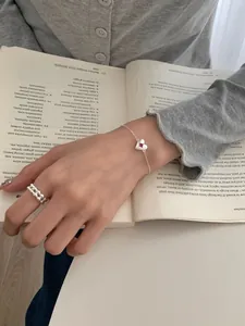 Detail of S925 silver heart bracelet with pink gemstone on a vintage book background