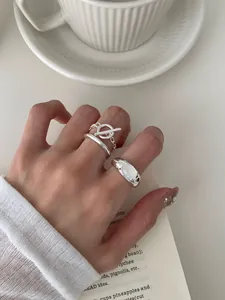 Detailopname van driedelige zilveren ringenset met ketting en witte steen op de hand