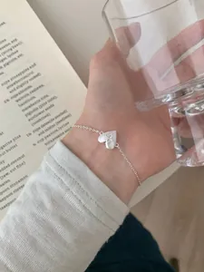 Macro detail of S925 sterling silver heart bracelet with square cubic zirconia on wrist