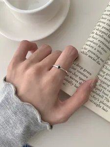 Dettaglio di un sottile anello in argento S925 con una piccola gemma nera sul dito