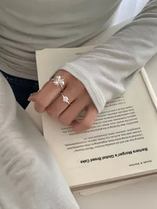 Detail van S925 zilveren bloemring en solitaire ring gedragen tijdens het lezen