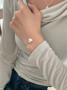 Detail view of a dainty S925 silver heart bracelet with a small zircon on a model's wrist