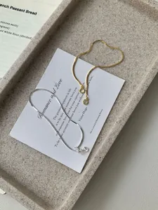 Detailed view of gold and silver snake bone chain bracelets with small sparkling crystal charms