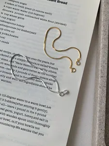 Detailed view of silver and gold snake chain bracelets with clear zircon pendants