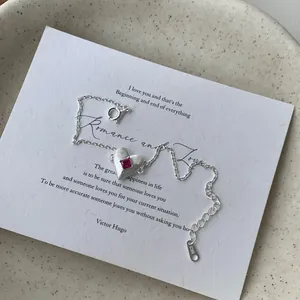 S925 sterling silver bracelet with red heart-shaped gemstone pendant on display card