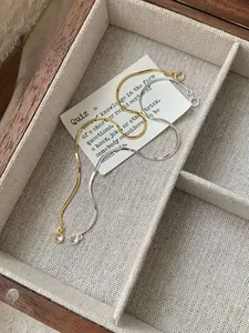 Detailed macro of gold and silver snake chain bracelets with round zircon charms in a box