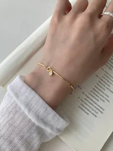 Detail of gold snake chain bracelet with a sparkling cubic zirconia pendant on wrist