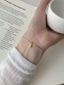 Detail of golden snake bone bracelet with a sparkling crystal pendant and spring clasp