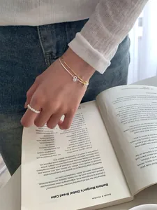 Macro shot of layered silver ring and dainty bracelets set against a vintage book