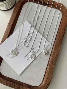 Dettaglio macro di collane con pendenti a cuore e conchiglia in argento S925