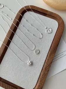 Dettaglio macro di ciondoli a cuore e conchiglia in argento S925 su catena sottile