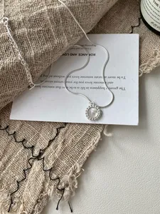 Dettaglio della collana S925 in argento con pendente tondo in conchiglia su tessuto grezzo