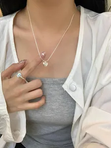 Dettaglio della collana con cuore in argento S925 su modella con anello in gemma azzurra