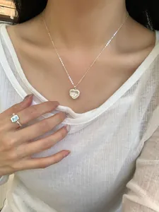 Dettaglio della collana con cuore in argento e anello con gemma blu sulla modella