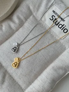Detail of silver and gold gourd necklaces with Fu character on textured fabric