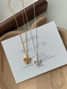 Detail of silver and gold fleur-de-lis necklaces with micro-pave diamonds on paper