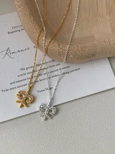 Close-up of gold and silver fleur-de-lis necklaces with zircon inlay on a wooden tray