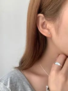 Dettaglio di orecchini a fiocco in argento S925 e anello regolabile su una modella
