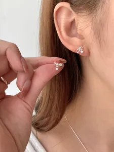 Dettaglio di orecchini a fiocco in argento con zircone indossati da una modella