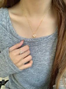 Detailed close-up of a delicate gold fleur-de-lis pendant necklace with sparkling diamonds