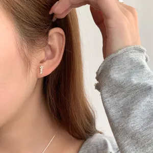 Orecchini a perno minimalisti in argento S925 con fiocco a cuore indossati da una modella