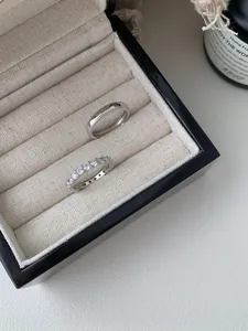 Macro shot of silver stackable rings with pavé cubic zirconia in a beige velvet jewelry box