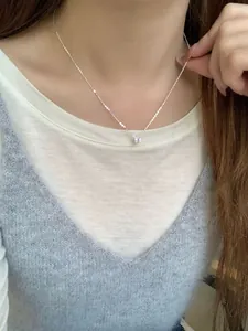 Primer plano de un collar solitario de diamante de carbono brillante puesto al cuello