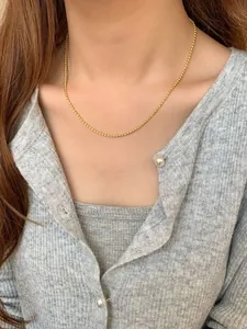 Close-up of golden S925 sterling silver ball chain necklace worn by a model