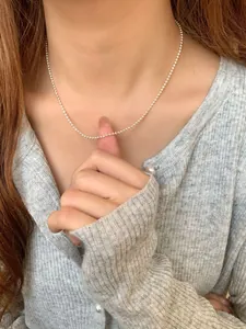 Detail of S925 sterling silver bead necklace chain on a woman's collarbone neck