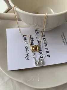 Gros plan détaillé des colliers pendentifs ondulés en argent sterling S925 dorés et argentés