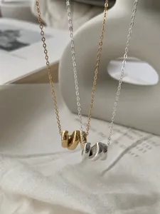 Gros plan sur des colliers en argent sterling S925 avec des pendentifs ondulés empilés