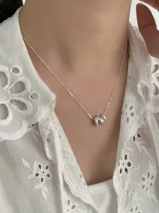 Gros plan du collier en argent S925 à nœud ondulé triple couche porté par un modèle