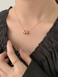 Détail d'un collier géométrique doré à plusieurs rangs et d'une bague sur un mannequin
