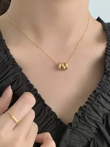 Détail d'un collier en or avec pendentif triple anneau poli sur une chaîne délicate