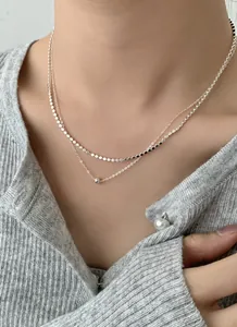 Macro di una collana a due strati in argento con pendente a sfera minimalista e piccoli dischi