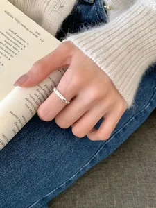 Close-up of sparkling S925 silver ring with textured engraving worn while reading a book