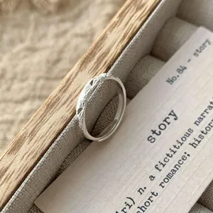 Minimalist S925 sterling silver ring featuring engraved star patterns on a wooden box