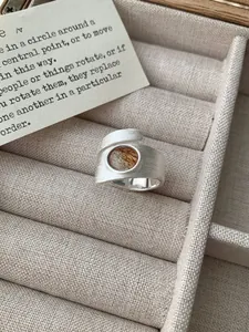 Détail macro d'une bague large en argent avec quartz rutilé rond et finition brossée