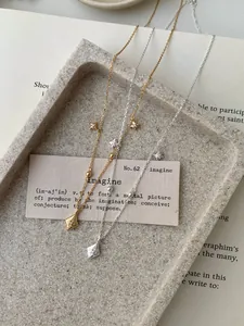 Détails de colliers S925 or et argent présentés sur un plateau minimaliste en pierre