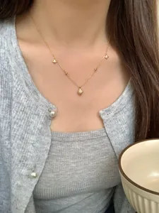 Détail du collier étoile S925 sur tricot gris avec pendentifs étoile et losange