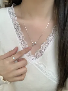 Detail van S925 zilveren ketting met minimalistische parel en cilinder hanger op model