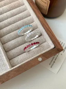Trois bagues éternité en argent S925 avec zircons colorés dans un écrin à bijoux en bois