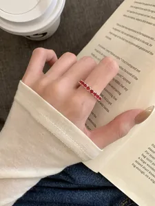 Détail d'une bague élastique en argent avec zircons rouges portée à l'index