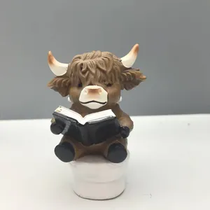 Detail of Highland Cow figurine sitting on a toilet reading a book bathroom decor