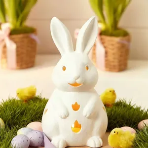 White ceramic Easter bunny candle holder with glowing LED cutouts on green grass