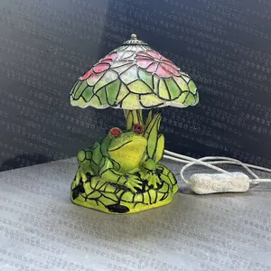 Close-up of Tiffany-style resin frog lamp base with intricate colorful glass floral shade